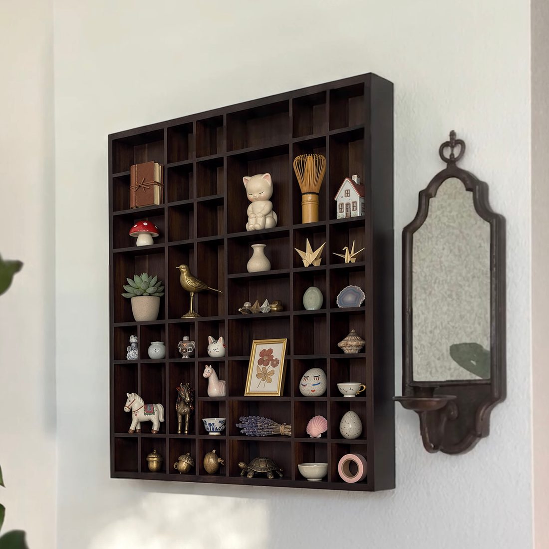 The Wondershelf on a wall, filled with small keepsakes, next to a mirror